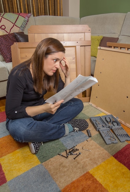 Chica leyendo instrucciones para montar muebles.