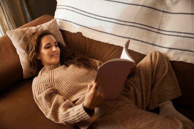 Chica leyendo en el sofá de casa