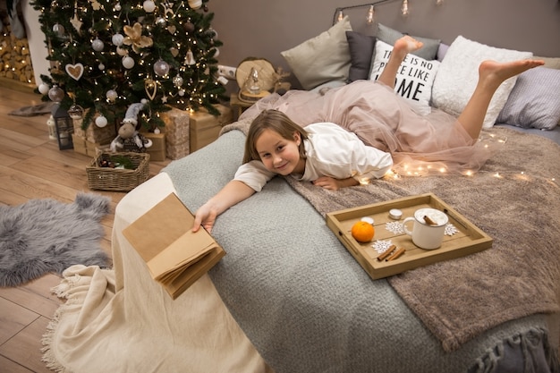 Chica con un libro acostado en la cama, desayuno en la cama, enfoque suave