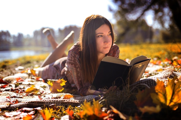 Chica con un libro en el follaje de otoño