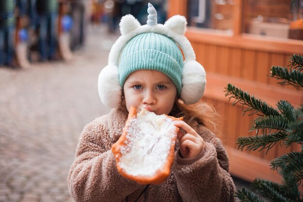 Foto chica linda de 4 años con ojos azules en un mercado europeo de navidad vacaciones año nuevo