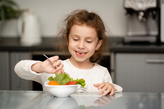 Una chica linda come una ensalada de verduras frescas. Comida sana. Infancia.