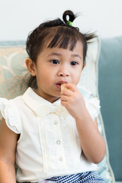 Una chica linda comiendo con los dedos en casa.