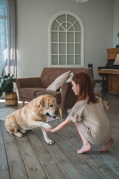 Foto una chica linda entrenando a un perro labrador en casa