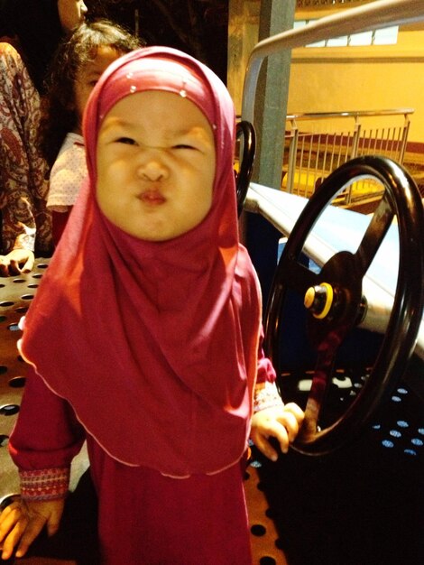 Chica linda con hijab haciendo cara en el coche en el parque de atracciones