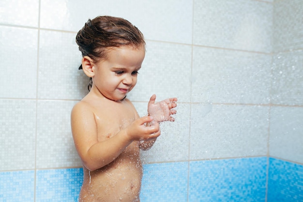 Foto una chica linda jugando con agua en el baño.