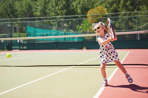 Una chica linda jugando al tenis y posando para la cámara.