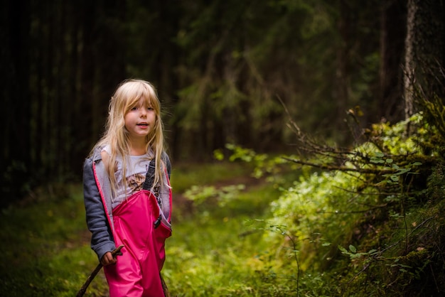 Chica linda de pie junto a las plantas en el bosque