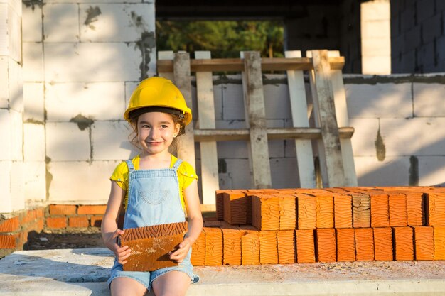 Foto una chica linda con ropa dura tenía un ladrillo en el sitio de construcción