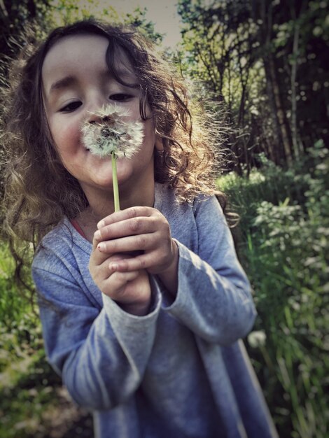 Chica linda con semilla de diente de león en el bosque