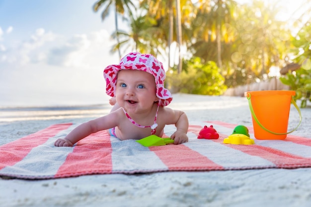 Una chica linda sonriente mirando hacia otro lado mientras está acostada en una toalla en la playa