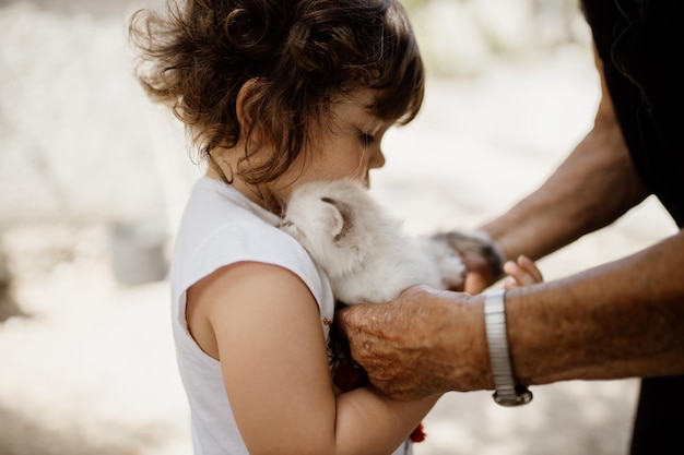 Foto una chica linda sosteniendo un gato con su abuelo.