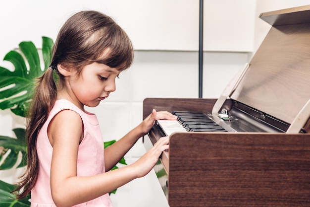 Una chica linda tocando el piano en casa.