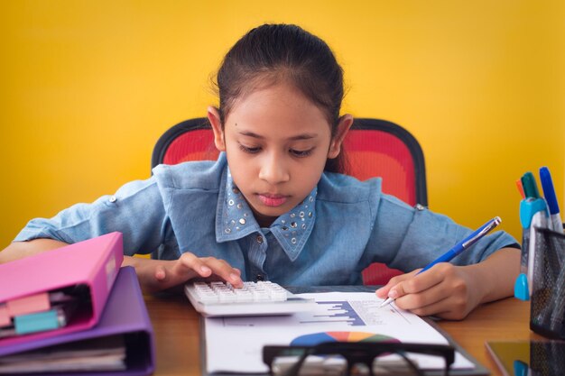 Foto chica linda trabajando con calculadora en el escritorio con documento aislado de fondo amarillo