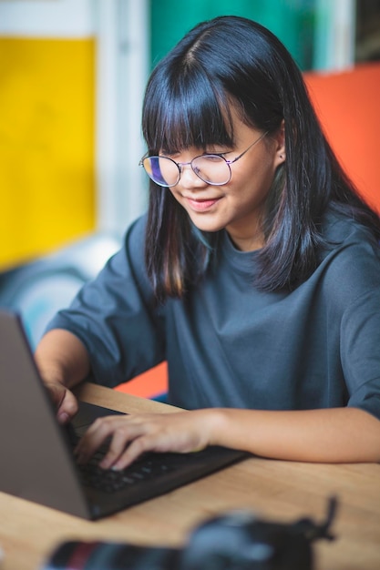 Foto una chica linda usando una computadora portátil en la mesa.