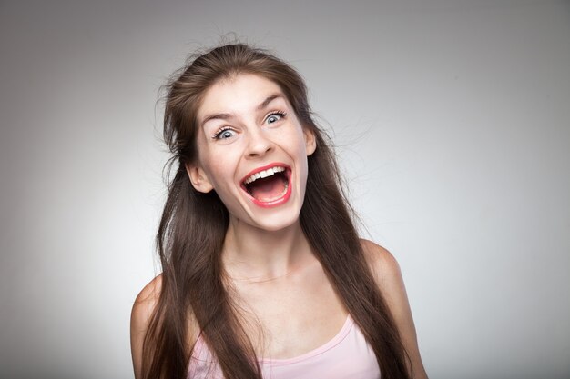 Chica loca gritando fuerte en retrato de estudio. Con fondo de viñeta gris.