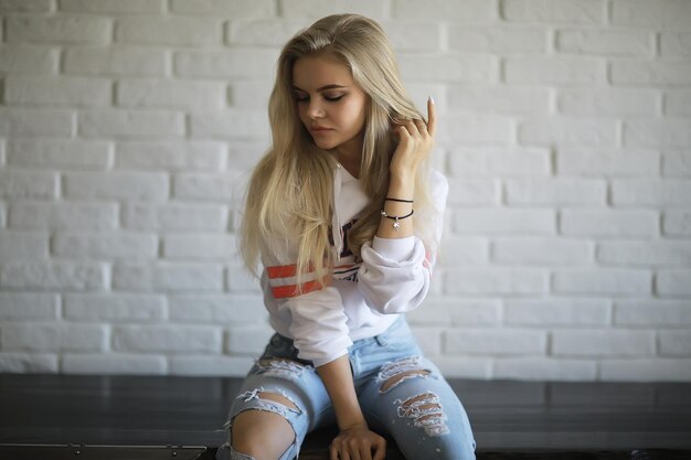 chica en un loft interior, casa moderna, ventanas, pared. adulto joven posando