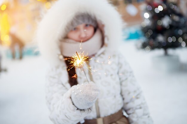 Chica con luces de Bengala de Navidad en ropa de invierno en la calle.