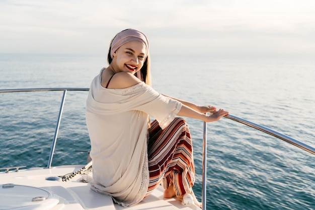 Chica de lujo feliz en ropa de verano con estilo se sienta en su yate navega en el mar Caribe