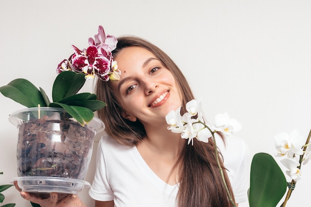 Chica con una maceta de orquídeas sobre fondo blanco.