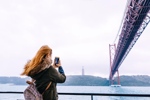 Una chica con un maletín en la espalda viaja y fotografía las vistas de la ciudad