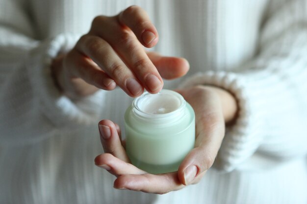 Chica mancha sus manos crema cosmética cuidado de la piel