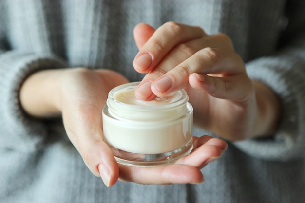 Chica mancha sus manos crema cosmética cuidado de la piel