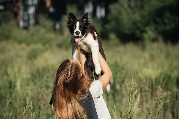 Chica mantenga en sus manos cachorro de perro border collie blanco y negro en el campo