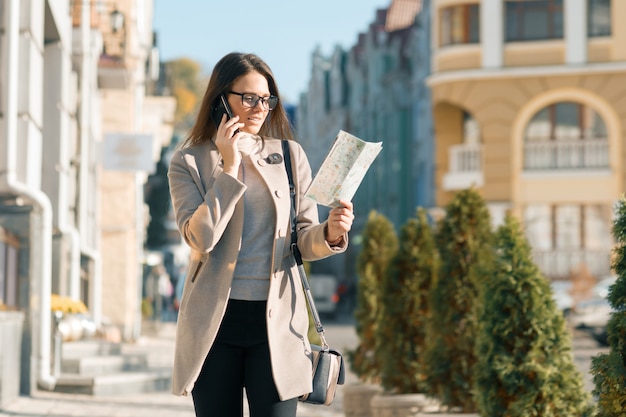 Chica con mapa turístico hablando por teléfono móvil