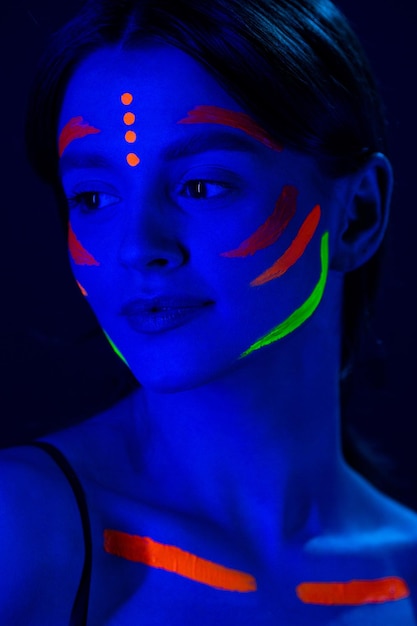 Chica con maquillaje fluorescente en la cara y el pecho