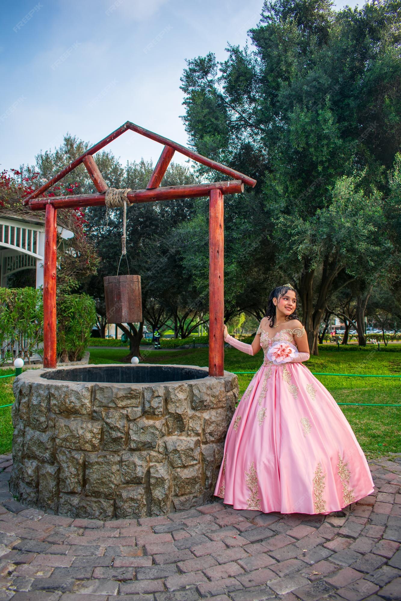 Chica con maquillaje y peinado con un vestido de princesa, cerca de un pozo los | Foto Premium