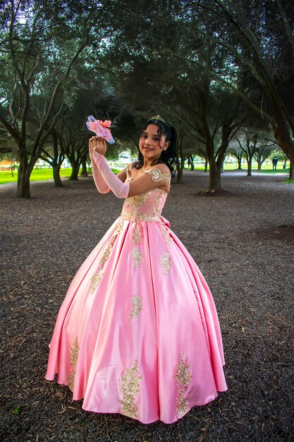 Chica con maquillaje y peinado con un vestido de princesa en medio de un parque y árboles verdes