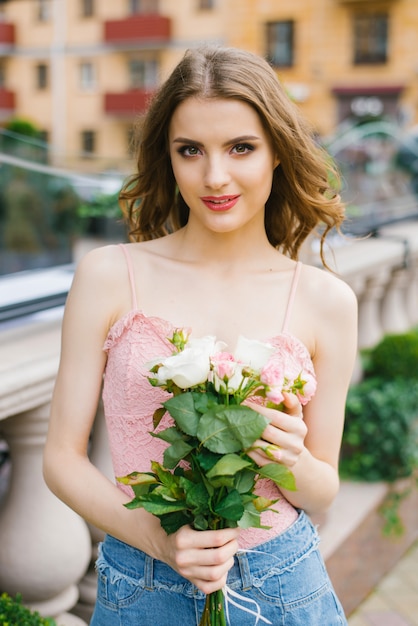 Chica con maquillaje con un ramo de rosas blancas y rosadas