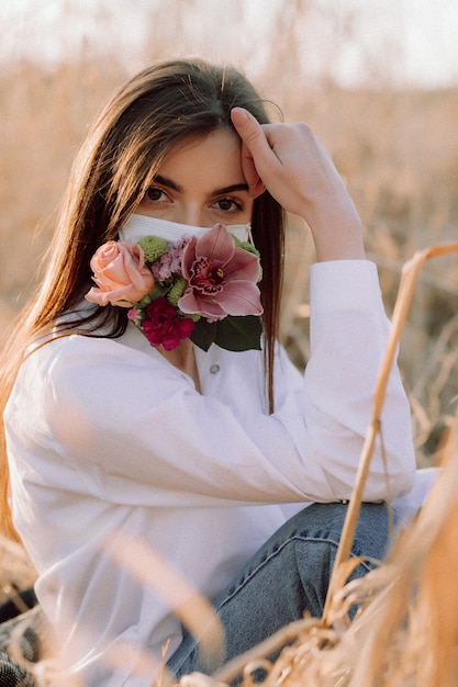 Chica en una máscara médica con flores.