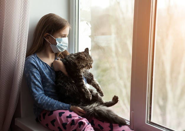 Chica en máscara médica con gato y sufre de alergia en casa