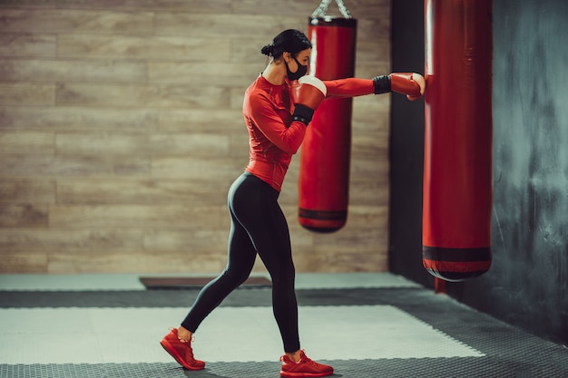 Chica con una máscara médica y guantes de boxeo.