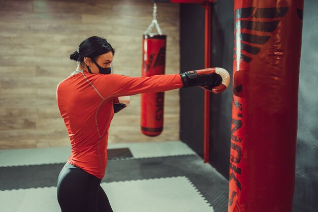 Chica con una máscara médica y guantes de boxeo.