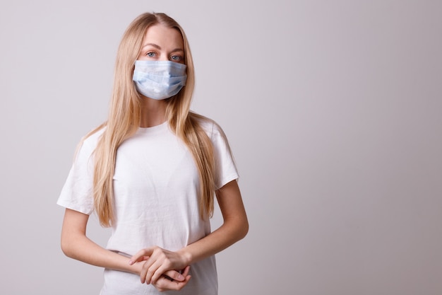 Chica con una máscara médica en una pared gris