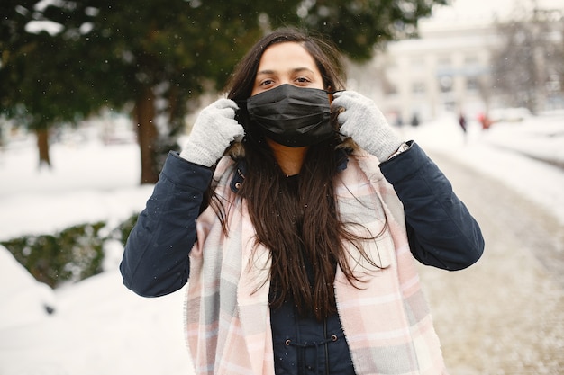 Chica con máscara. Mujer india en ropa de abrigo. dama de la calle en invierno.