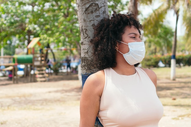 Chica con una máscara protectora y de pie en el parque.