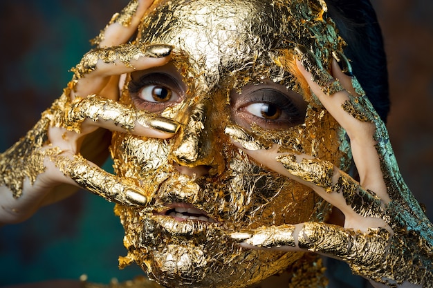 Chica con una máscara en el rostro hecha de pan de oro Sombrío retrato de estudio de una morena