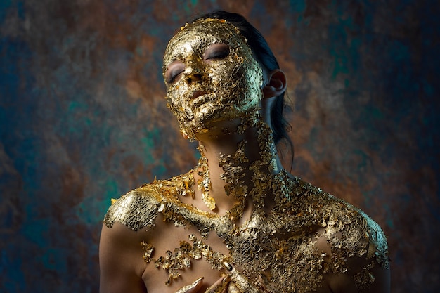 Chica con una máscara en el rostro hecha de pan de oro.