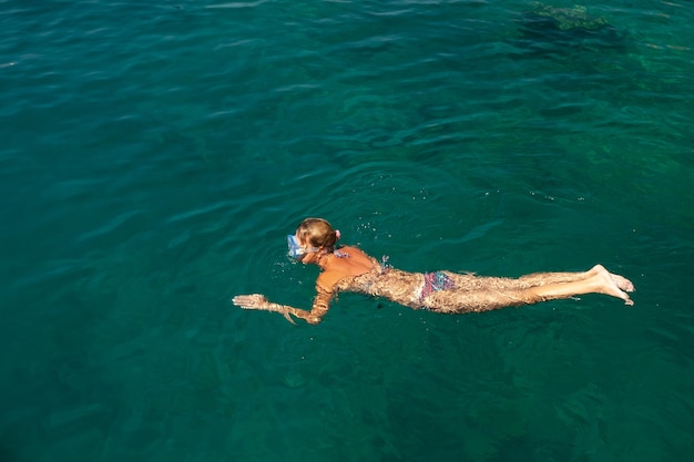 Chica en una máscara de snorkel nada en el mar