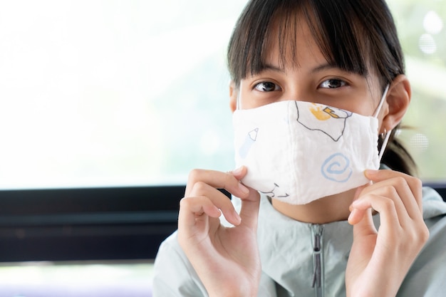 Chica bajo la mascarilla de algodón que cubre la boca y la nariz.