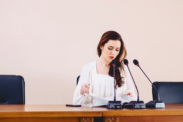 Chica en la mesa habla en micrófonos en la sala de conferencias