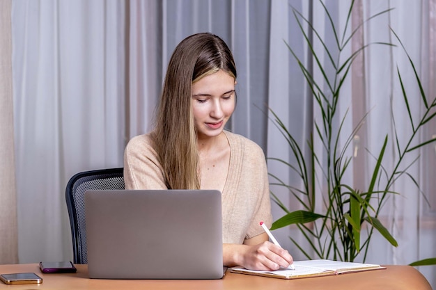 Chica en una mesa con una laptop estudiando en línea