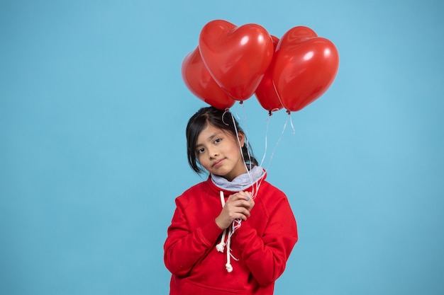 Chica mexicana sosteniendo un montón de globo corazón rojo