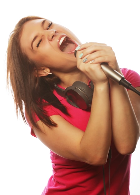 Chica con un micrófono cantando y divirtiéndose, aislado en blanco