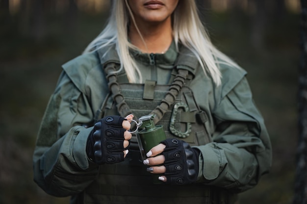 Foto una chica militar en uniforme con equipo de combate tiene una granada en la mano