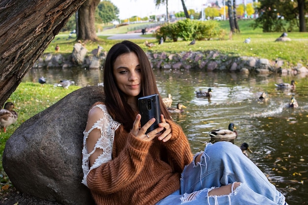 Chica mira el teléfono en la orilla del río